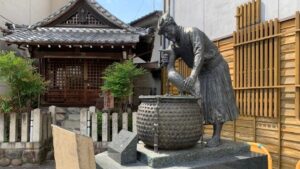 鵜飼観覧船事務所前に設置された鵜匠像と背景にある神社の建物