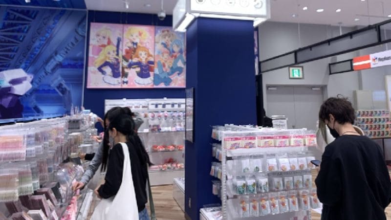 アイカツショップ名古屋の店内グッズ売り場と限定アイテムを選ぶ来店客の様子